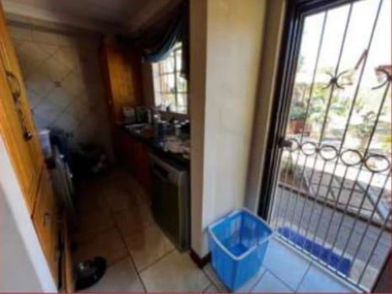 A functional scullery area featuring built-in cabinetry, tiled flooring, and direct access to the exterior through a security gate.