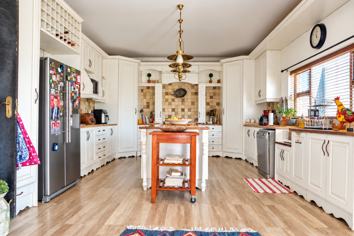 A spacious, well-lit kitchen featuring classic white cabinetry, a tiled backsplash, integrated appliances, and a central island, offering a functional and inviting culinary space.
