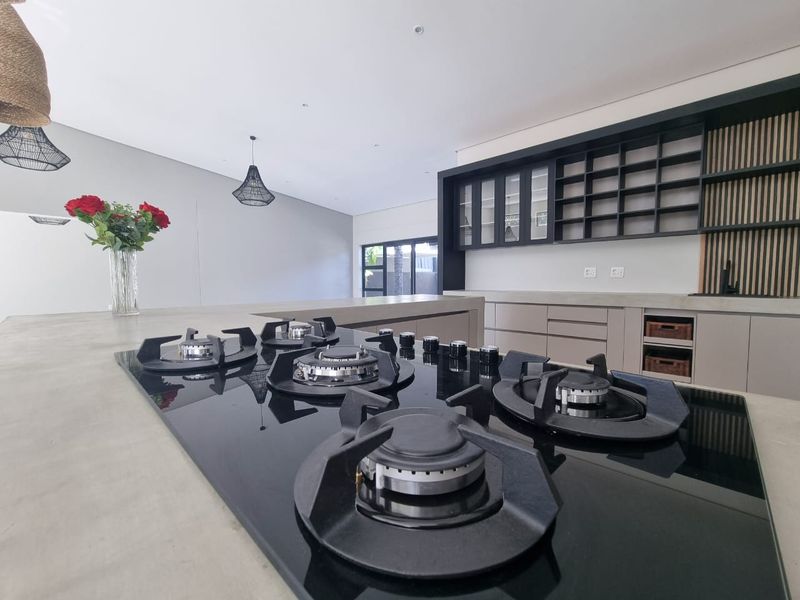Modern kitchen featuring a large concrete island with an integrated gas hob, custom cabinetry, and stylish slatted wood wall accents.