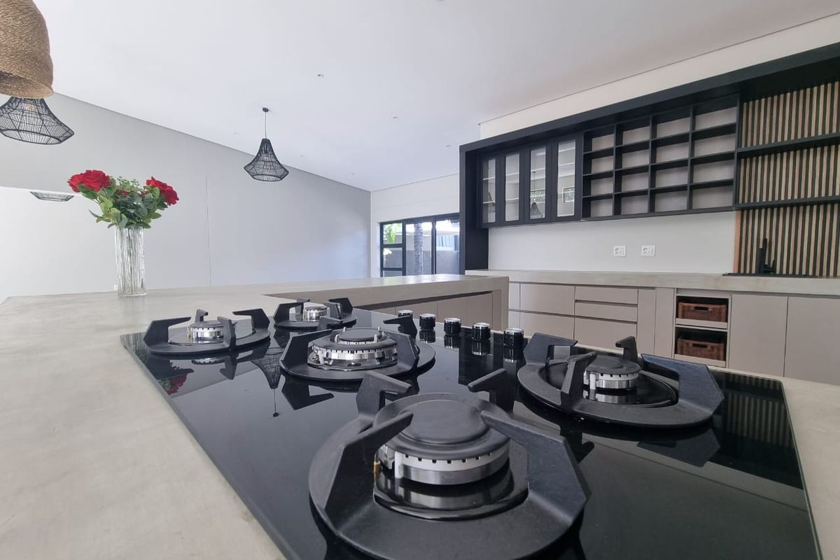 Modern kitchen featuring a large concrete island with an integrated gas hob, custom cabinetry, and stylish slatted wood wall accents.