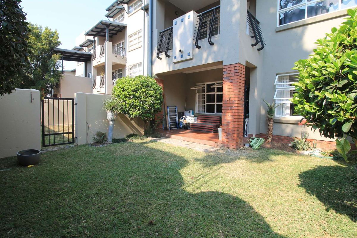 A private ground floor apartment garden featuring a covered patio area, brick pillar detailing, and a secure gated entrance.