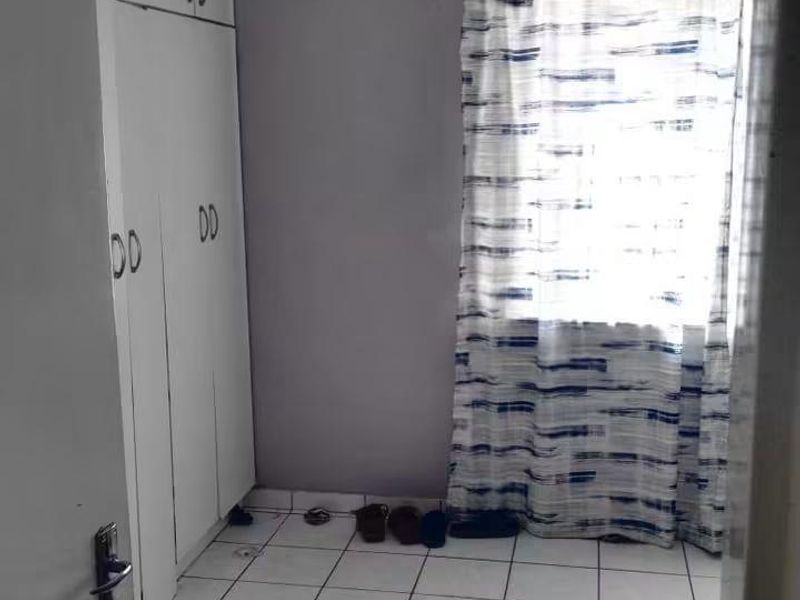 A compact bedroom featuring built-in cupboards and tiled flooring, offering a functional space ready for personalization.