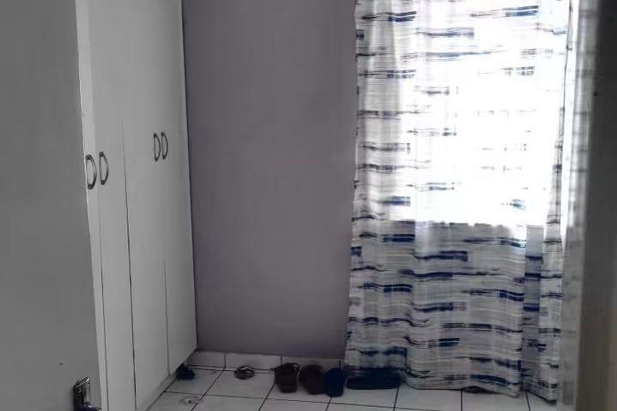 A compact bedroom featuring built-in cupboards and tiled flooring, offering a functional space ready for personalization.