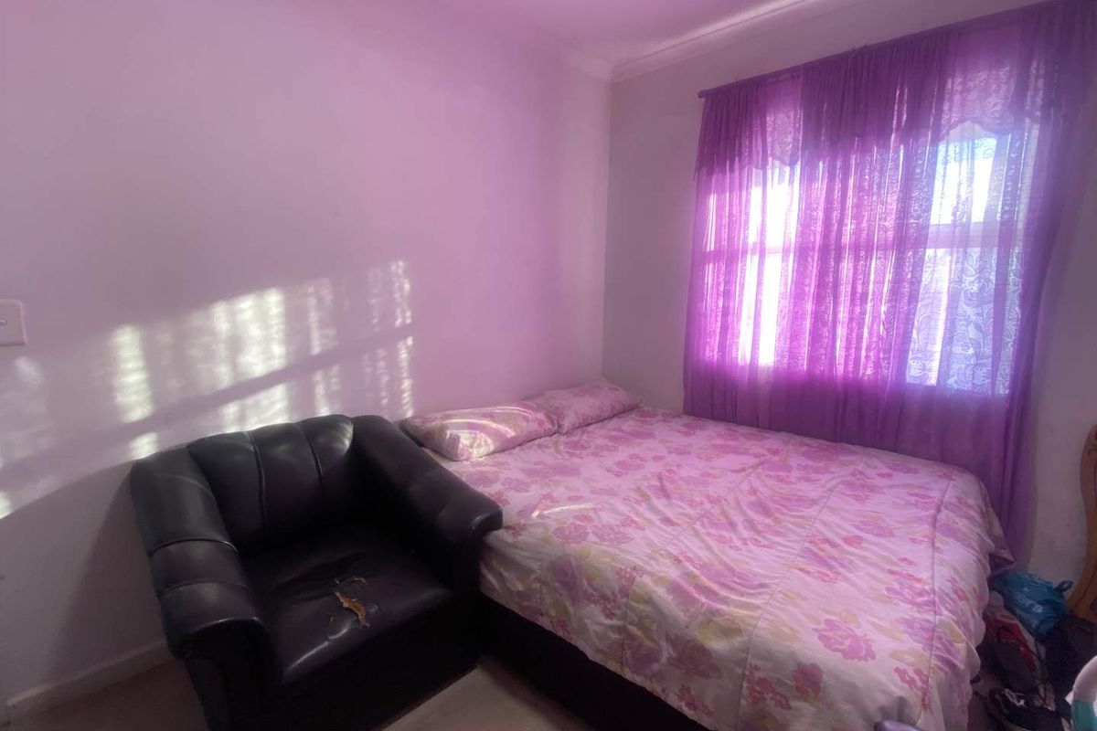 A bedroom featuring a window with purple curtains and light-colored flooring.