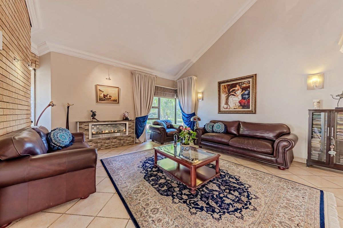 Spacious living room featuring a vaulted ceiling, tiled flooring, and a built-in fireplace with a brick feature wall.
