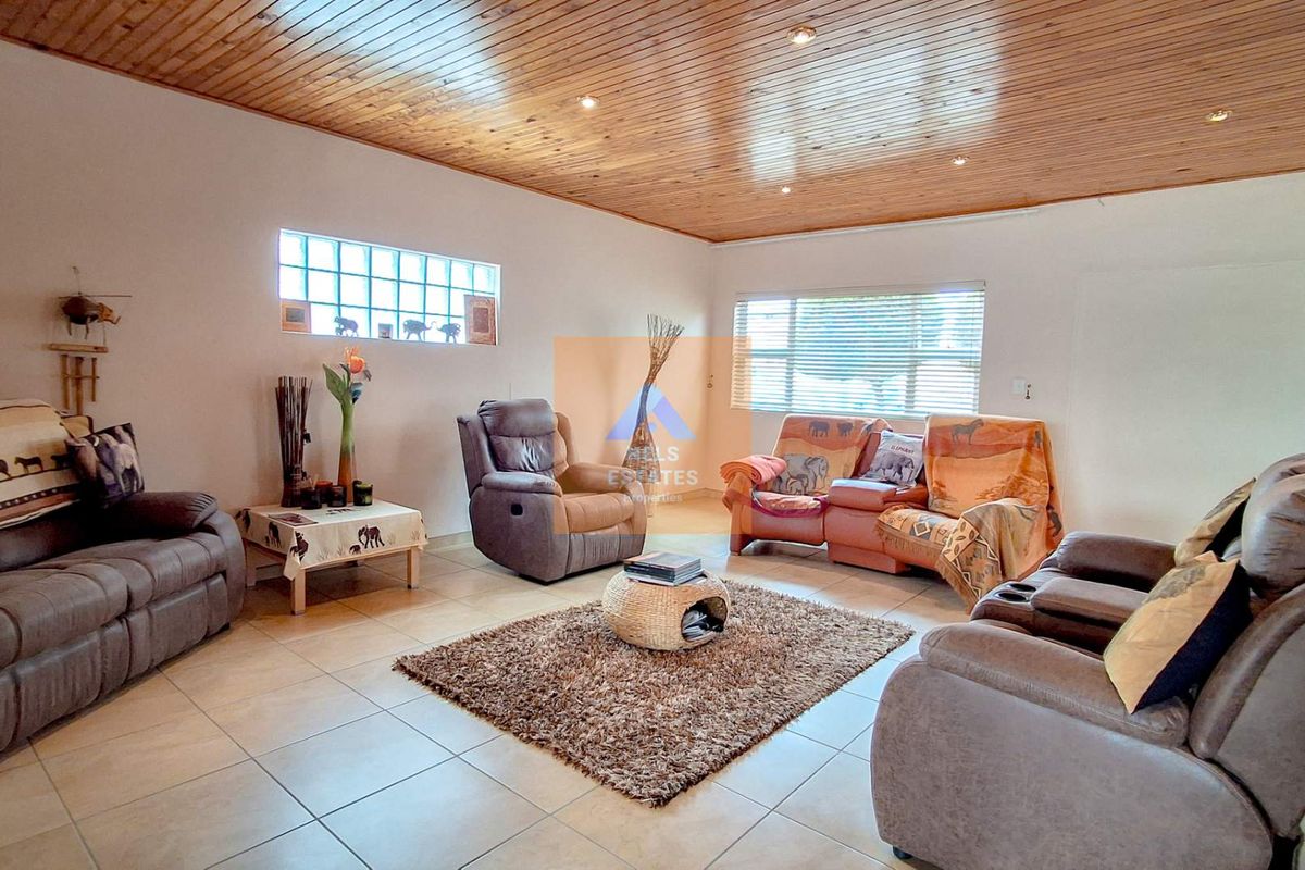 Spacious living room featuring a distinctive timber-clad ceiling, recessed downlights, tiled flooring, and a unique glass block window detail.