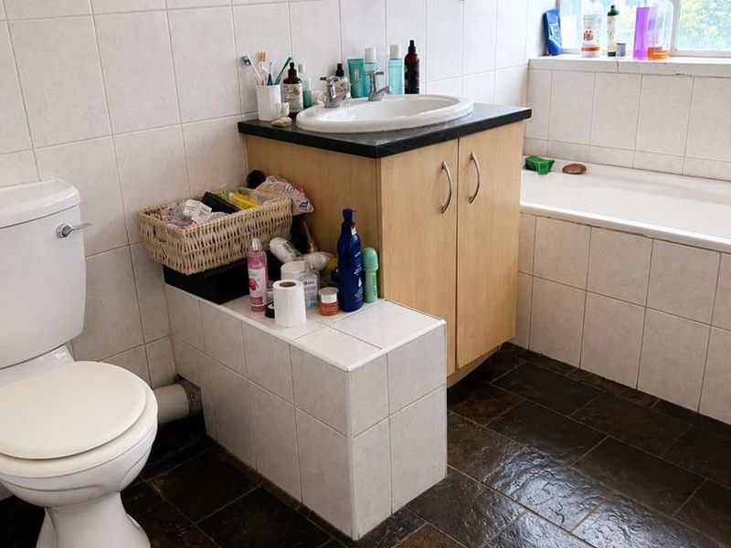 A functional bathroom featuring a built-in vanity, bathtub, and tiled finishes. The space offers a practical layout with natural light from the window.
