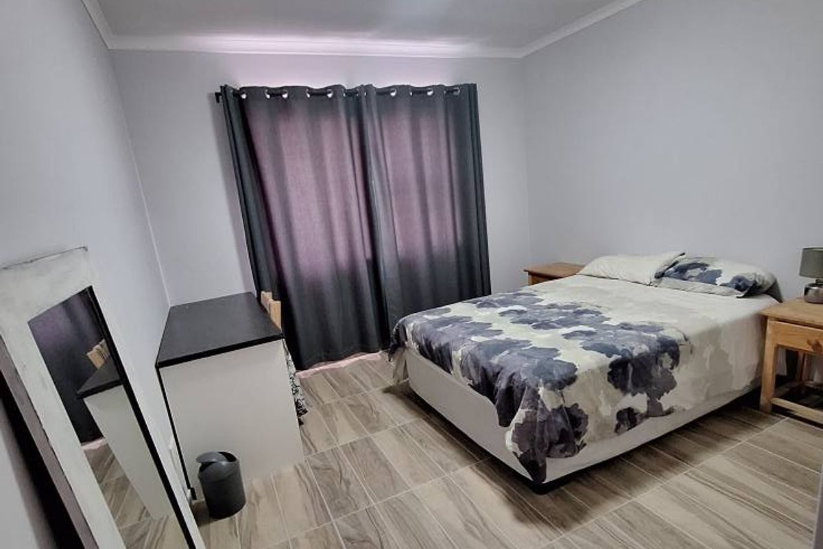 A bedroom featuring neutral wall paint, tiled flooring, and a window with curtains.
