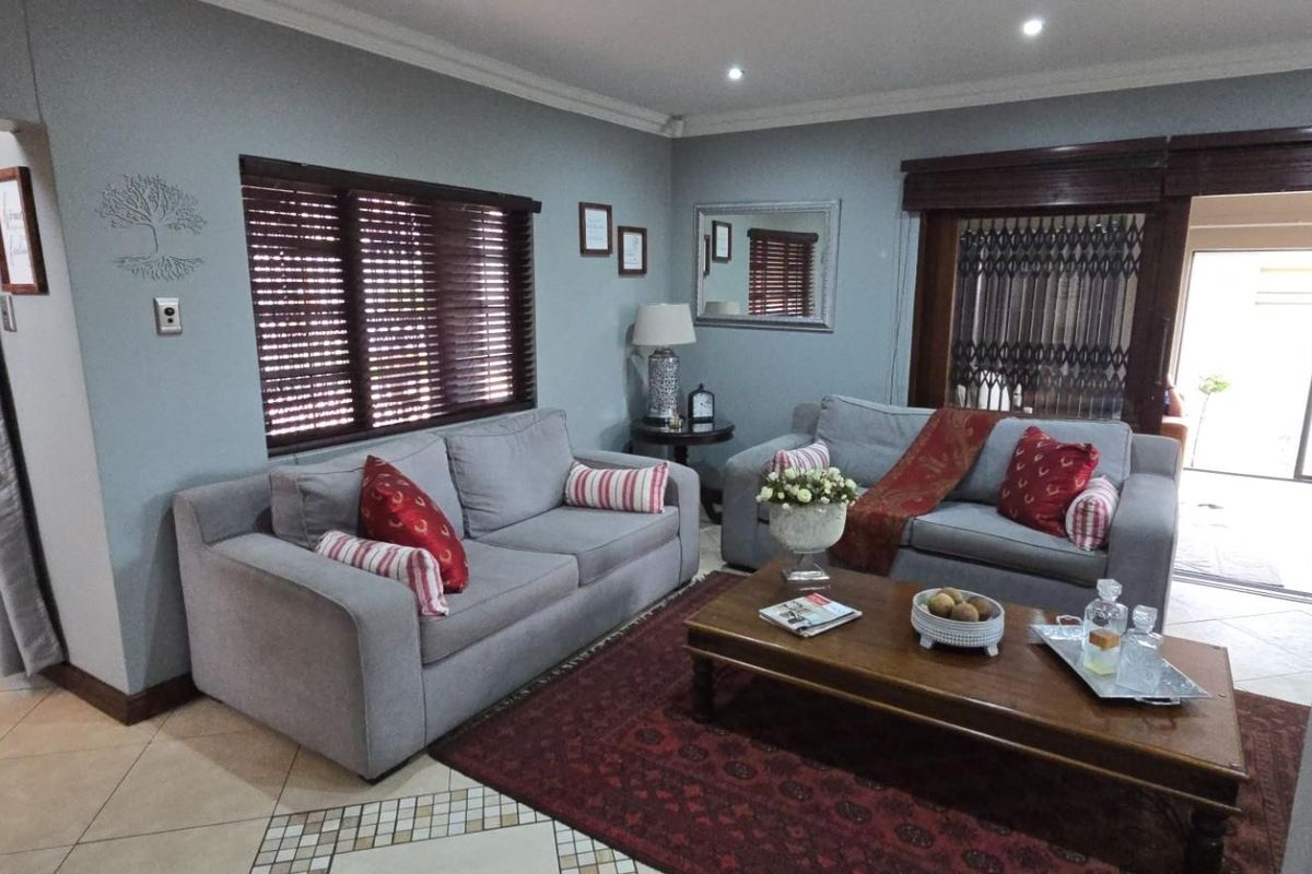 A comfortable living room featuring tiled flooring, recessed downlights, and timber venetian blinds, providing a well-maintained and inviting space.