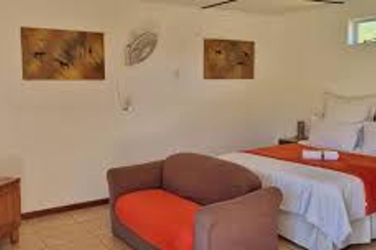 A spacious bedroom featuring tiled flooring, a ceiling fan, and a high-positioned window, providing a functional and comfortable living space.