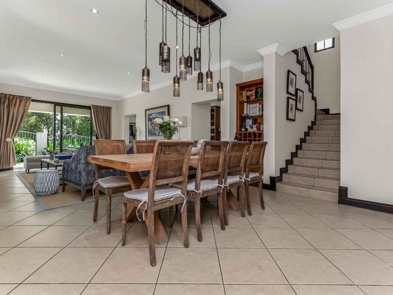 Spacious open-plan dining and living area featuring tiled floors, a feature staircase, and direct access to the outdoor patio through sliding glass doors.