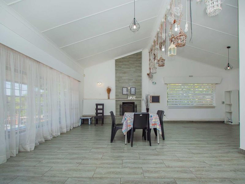 Spacious living area featuring a vaulted ceiling, tiled flooring, and a prominent stone-clad fireplace, offering a bright and open atmosphere.