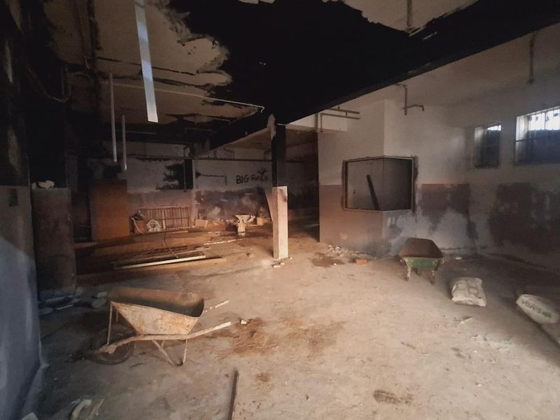A vacant industrial utility space featuring exposed ceilings, concrete flooring, and significant wear, suitable for renovation or repurposing.