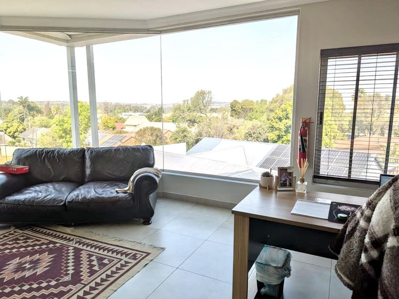 Bright office space featuring large floor-to-ceiling windows with expansive views, tiled flooring, and integrated venetian blinds.