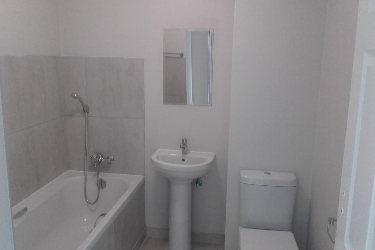 A functional bathroom featuring a bathtub with shower attachment, a pedestal basin, and a standard toilet.