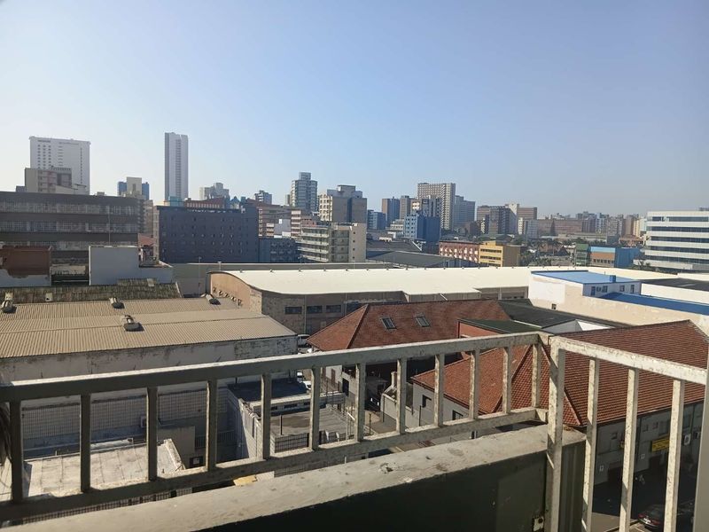 An elevated urban cityscape view captured from a balcony with a metal safety railing.