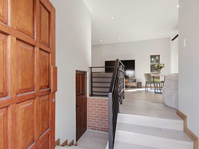 Welcoming entrance area featuring a solid timber door, modern metal balustrade, and a unique exposed brick accent wall leading to the main living space.