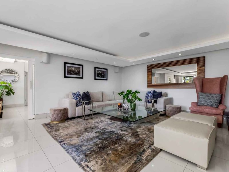 A modern, well-maintained living room featuring polished porcelain floor tiles, recessed ceiling lighting, and elegant cove detailing.