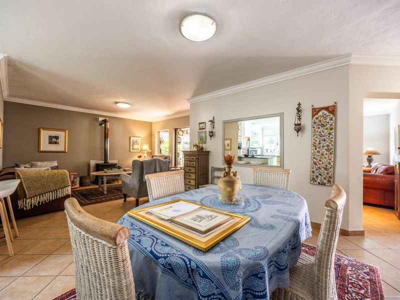 Spacious open-plan living and dining area featuring tiled flooring, a wood-burning stove, and an interior window connecting to the kitchen.