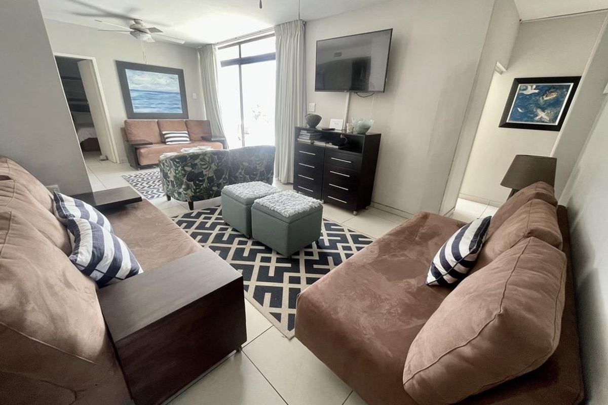 A comfortable living room featuring tiled flooring, a ceiling fan, and large sliding glass doors that provide access to the outdoor area.