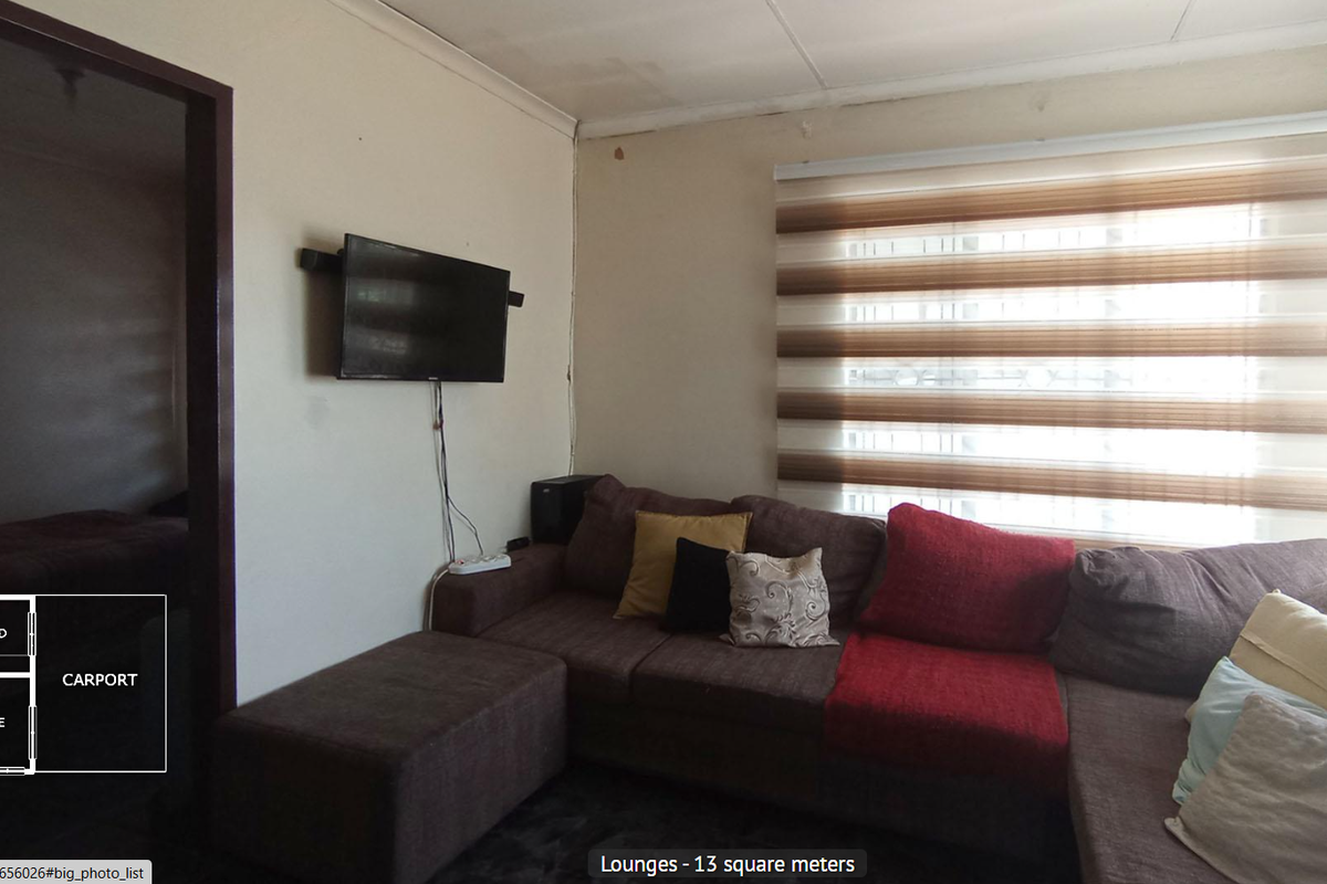 A compact living room featuring a wall-mounted television, neutral wall finishes, and large windows with fitted blinds.