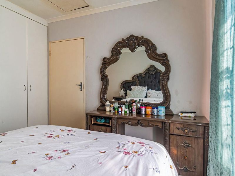 A bedroom featuring built-in cupboards and a ceiling access hatch, with neutral wall finishes and standard interior door.