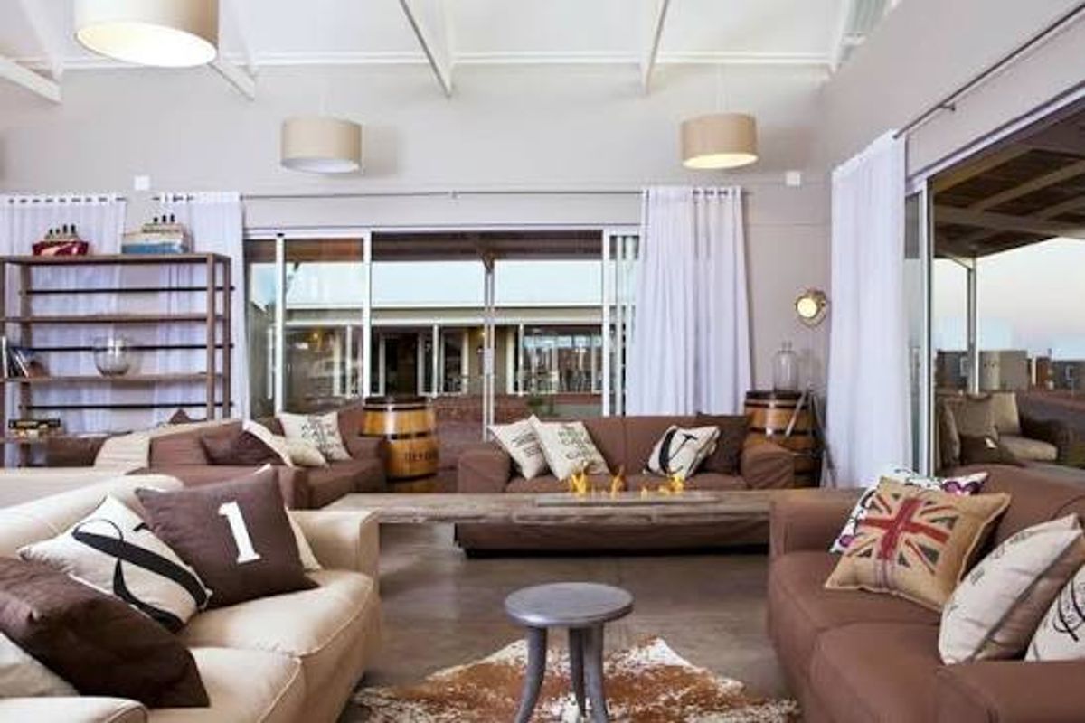 Spacious living area featuring vaulted ceilings with exposed rafters, polished concrete floors, and large sliding glass doors opening to an outdoor patio.