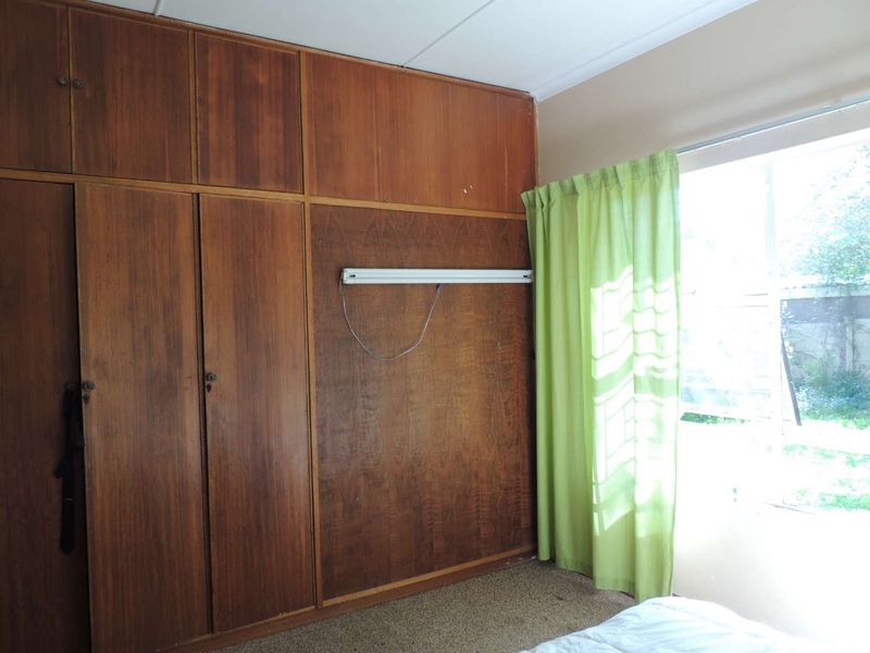 Bedroom featuring extensive built-in wooden cabinetry and a large window, offering potential for modernization and updated finishes.