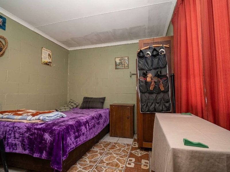 A bedroom featuring exposed blockwork walls and tiled flooring, requiring cosmetic updates to the ceiling and wall finishes.