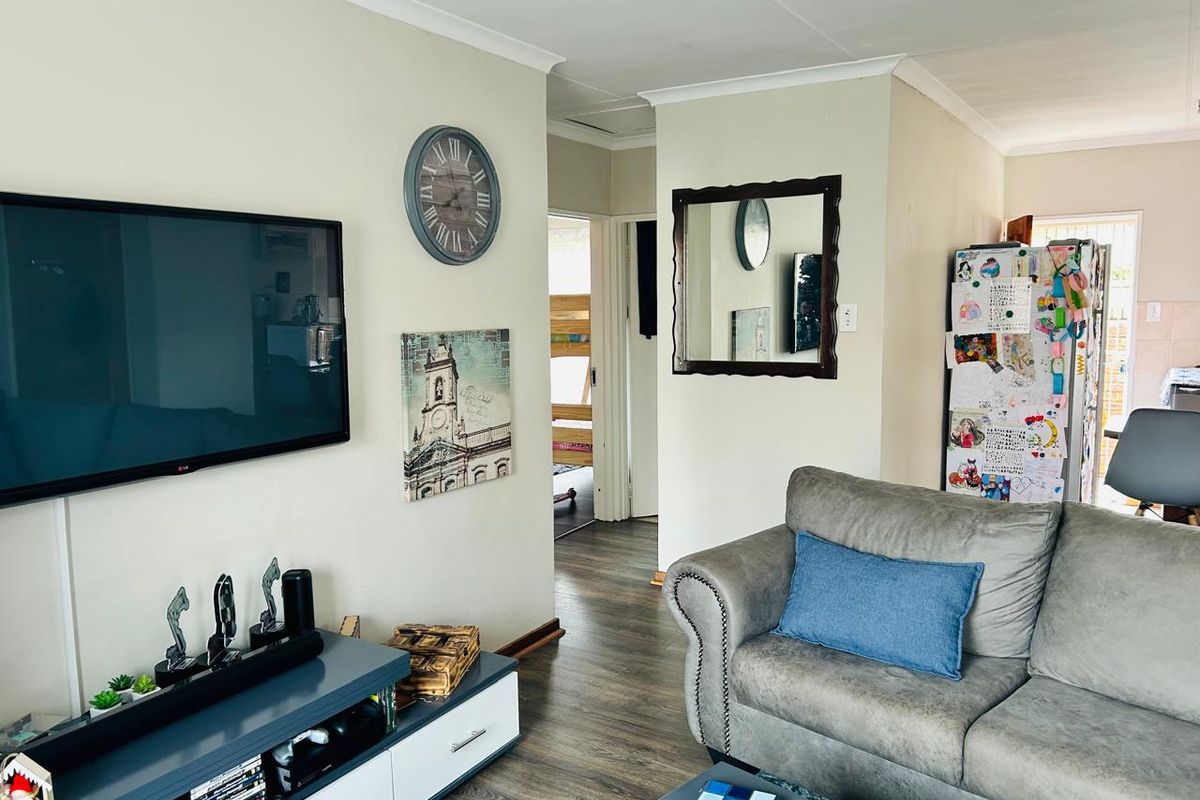 A view of the living area featuring wood-look flooring, coved ceilings, and a central hallway leading to the bedroom area.