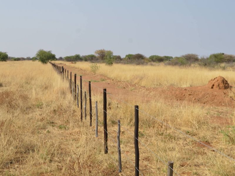 A view of the expansive agricultural land featuring established wire fencing with wooden posts, set against a natural dry grass landscape.