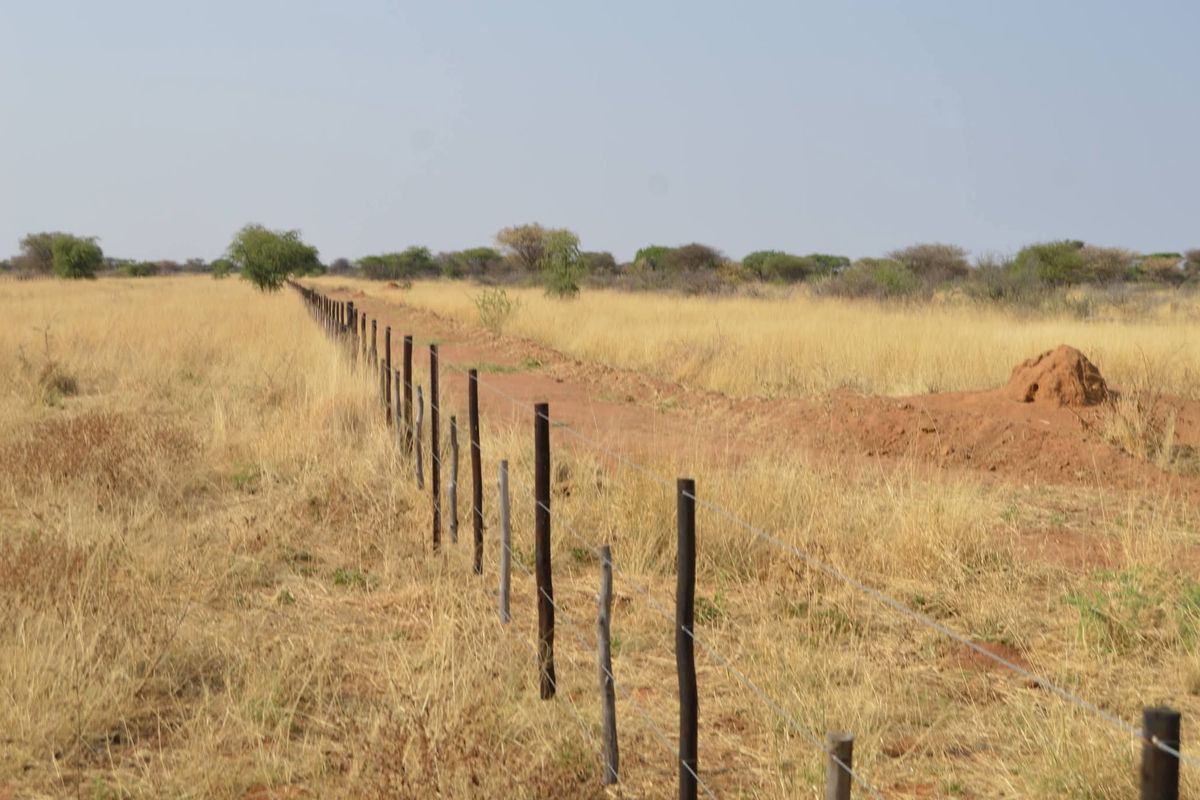 A view of the expansive agricultural land featuring established wire fencing with wooden posts, set against a natural dry grass landscape.
