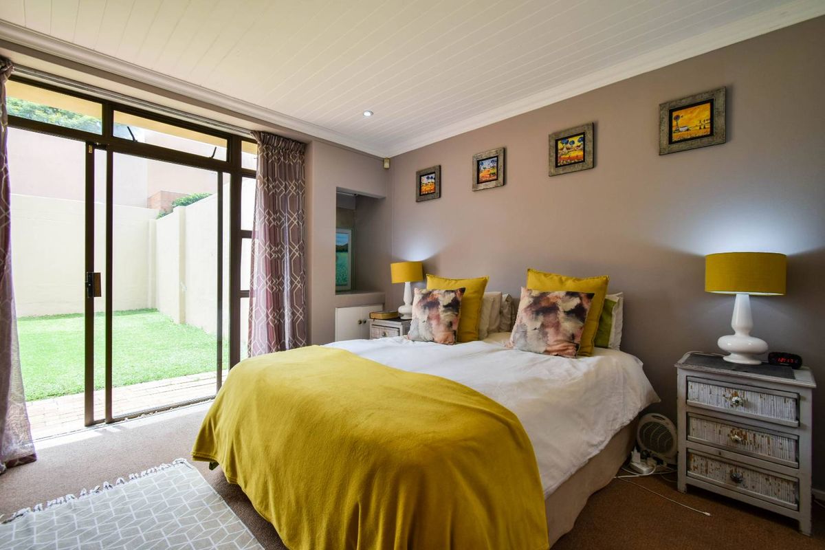 A well-maintained bedroom featuring a tongue-and-groove ceiling, neutral wall finishes, and large sliding glass doors providing direct access to the rear garden.
