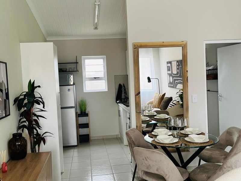 An open-plan living and dining area featuring tiled flooring, a high tongue and groove ceiling, and neutral wall finishes.