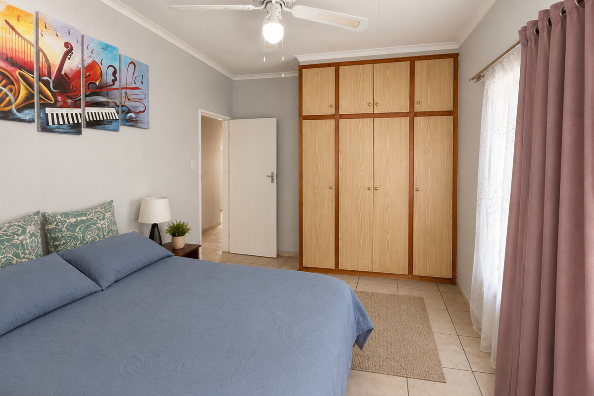 A well-maintained bedroom featuring built-in wooden cabinetry, tiled flooring, and a ceiling fan, offering a functional and comfortable living space.