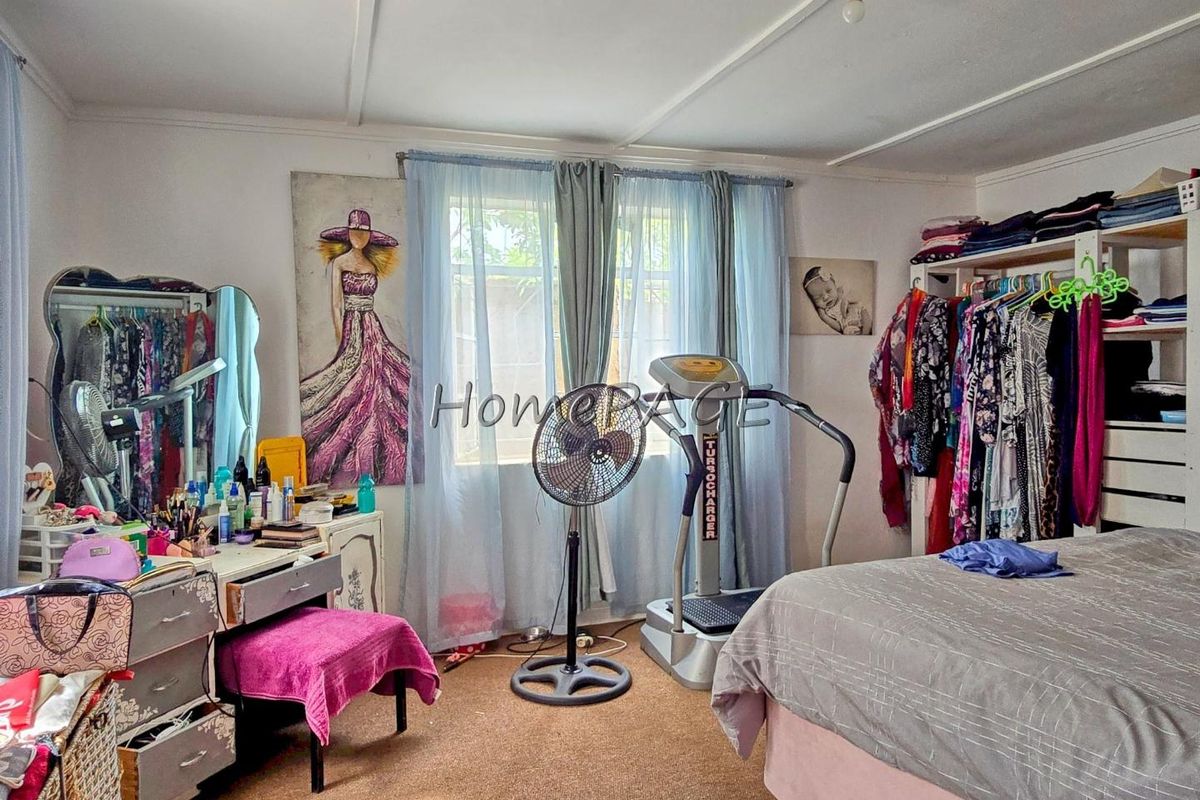 A bedroom featuring carpet flooring and a window with natural light, currently utilized as a multi-purpose living and storage space.