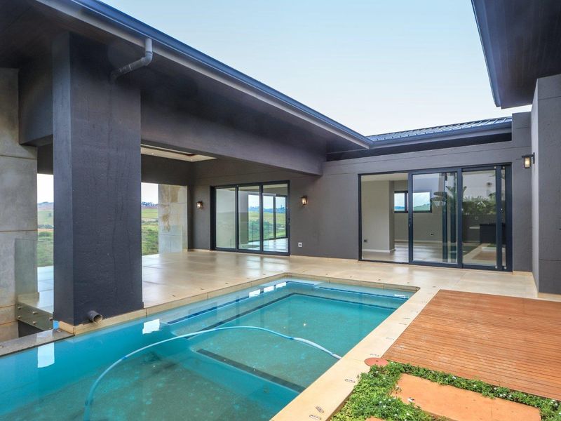 Modern outdoor entertainment area featuring a swimming pool, timber decking, and a spacious covered patio with large sliding glass doors.