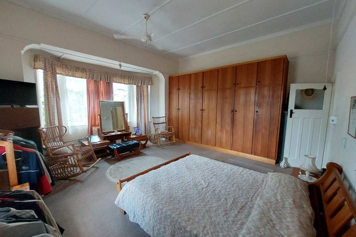Spacious bedroom featuring extensive built-in wooden cabinetry, large windows with natural light, and neutral carpeting.
