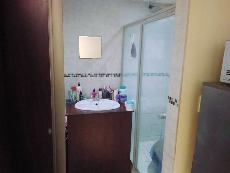 A functional bathroom featuring a vanity cabinet with a basin and a separate shower enclosure with tiled walls and a mosaic border.