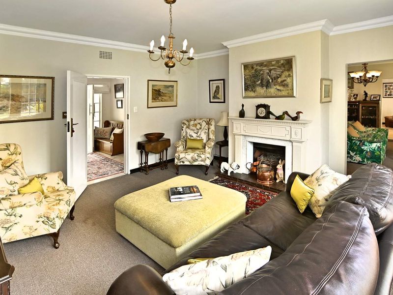 A traditional living room featuring a central fireplace with a decorative mantelpiece, crown molding, and a classic chandelier.