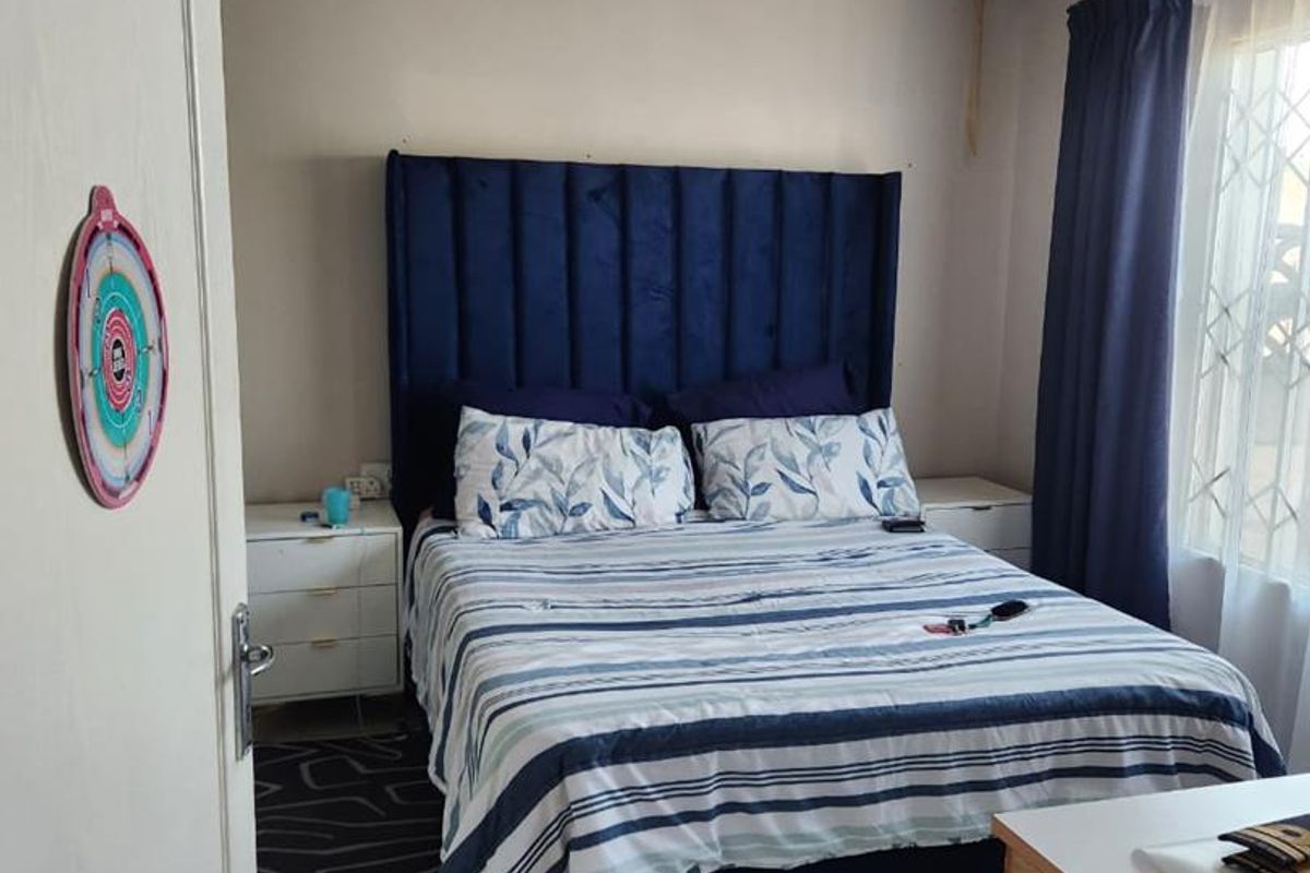 A bedroom featuring tiled flooring and a decorative ceiling finish, with a window providing natural light and security bars.