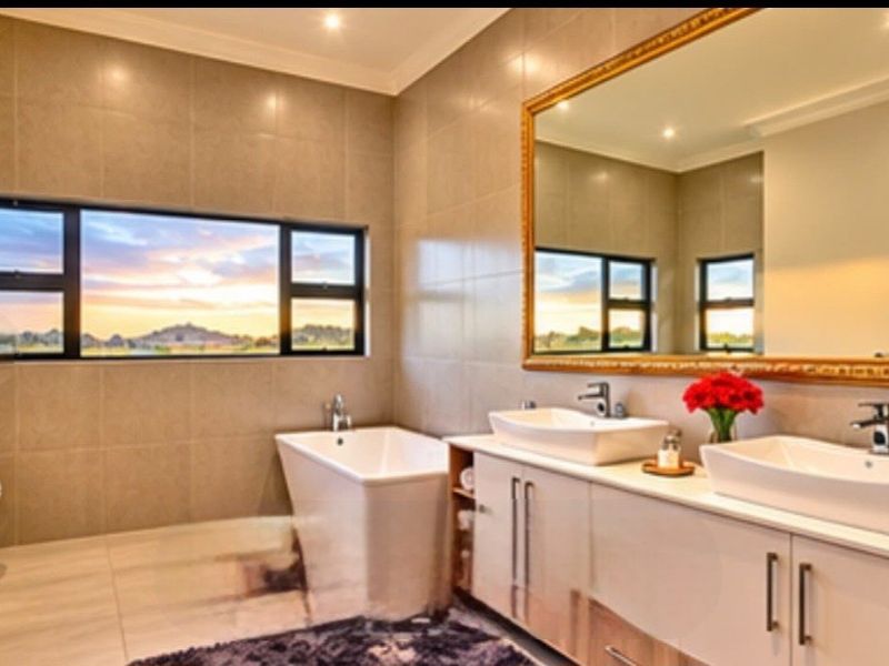 Modern bathroom featuring a double vanity with vessel sinks, a freestanding bathtub, and large windows offering scenic views.