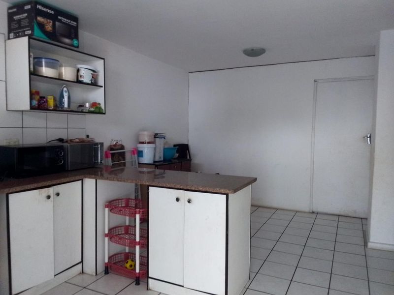 A functional kitchen area featuring white built-in cabinetry, granite countertops, and tiled flooring, providing a practical space for meal preparation.