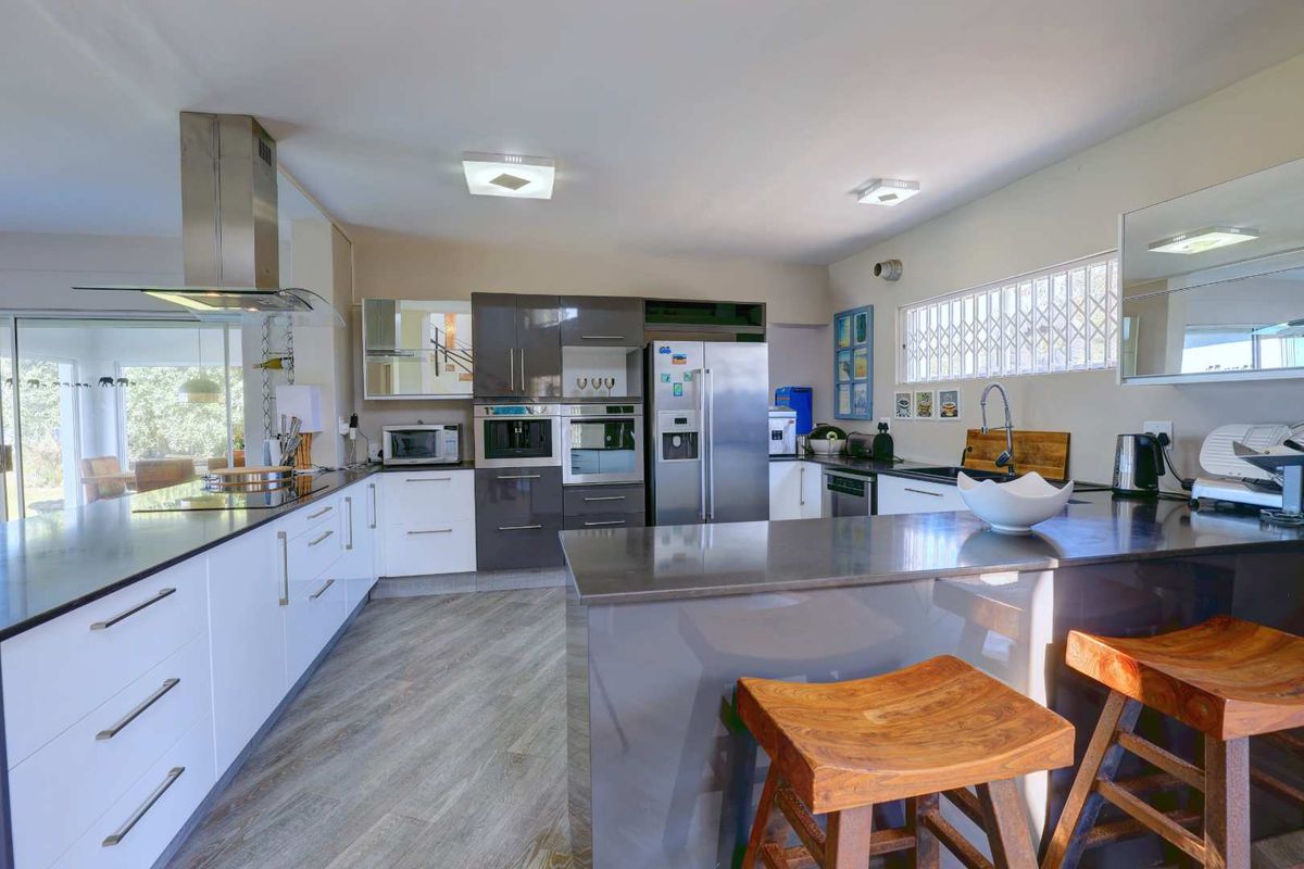 Modern kitchen featuring a large island, stone countertops, built-in appliances, and sleek cabinetry, offering a functional and contemporary cooking space.