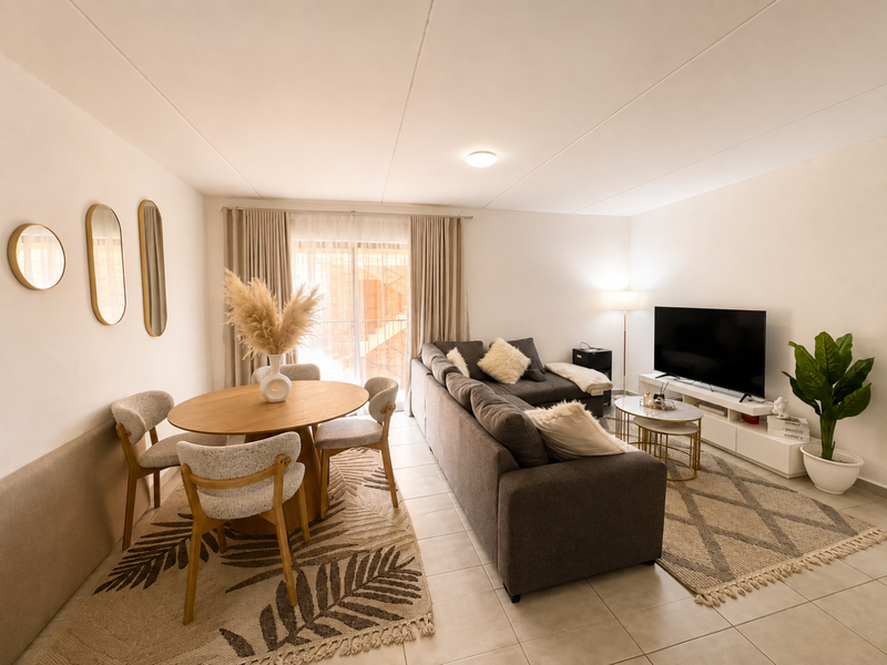 An open-plan living and dining area featuring tiled flooring, neutral walls, and a sliding glass door providing access to the exterior.