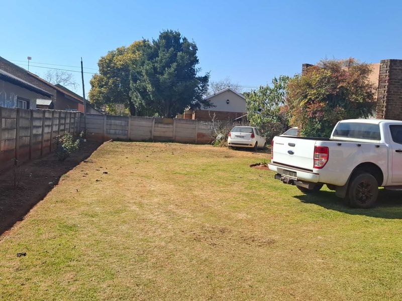 A spacious rear garden area featuring a large lawn enclosed by precast concrete boundary walls.