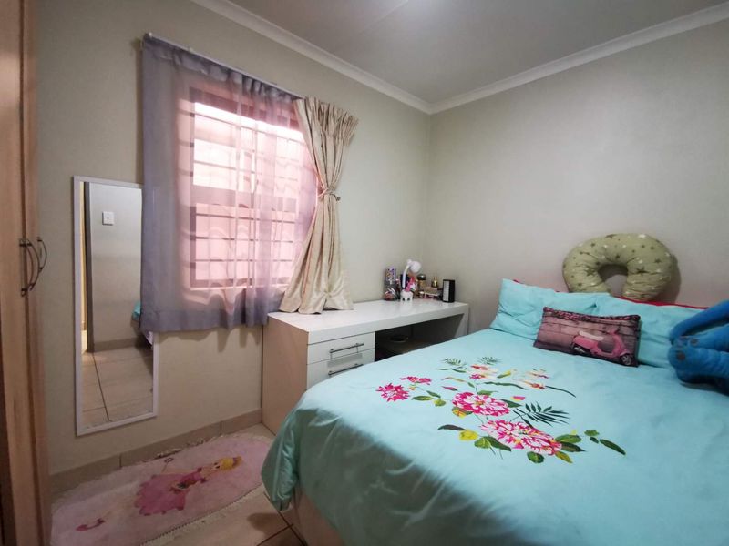 A functional bedroom featuring tiled flooring, a built-in wardrobe, and a window fitted with security bars.
