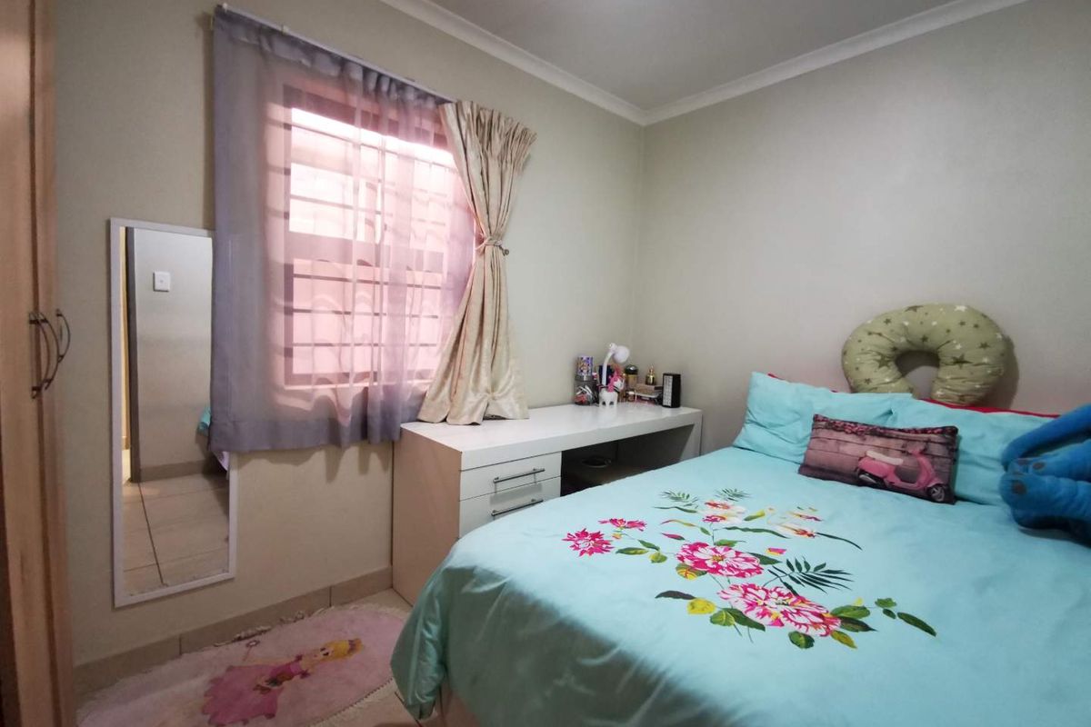 A functional bedroom featuring tiled flooring, a built-in wardrobe, and a window fitted with security bars.