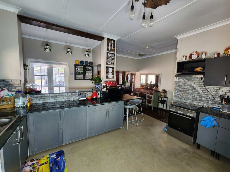 A functional kitchen featuring granite countertops, a built-in oven, an extractor fan, and a breakfast bar, complemented by an exposed timber beam.