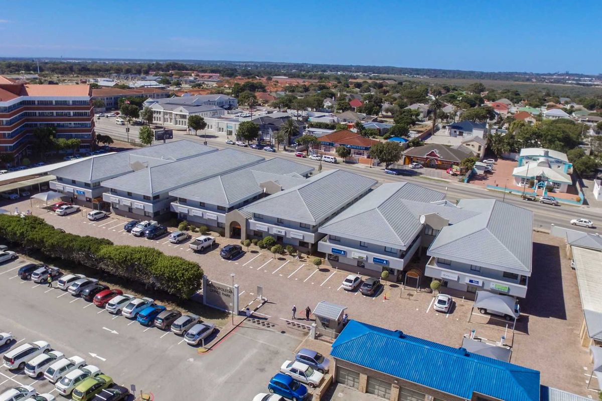 Aerial view of a multi-unit office park complex featuring pitched tiled roofs, paved parking areas, and convenient street access.